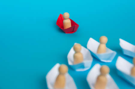 Leadership concept - People figure on red paper ship origami leading the rest of the people figure...