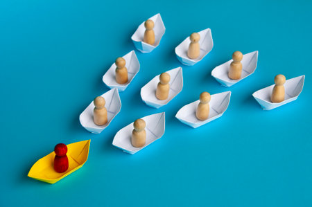 Leadership Concept - Red people figure on yellow paper ship origami leading the rest of the people...