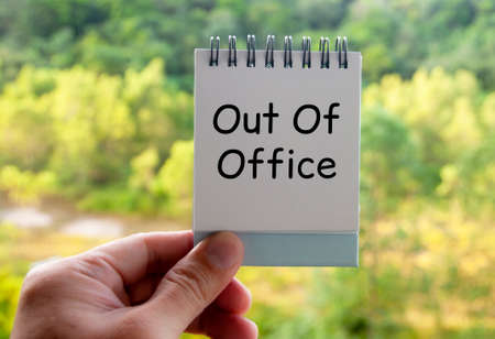 Out of office text on calendar desk with blurred nature background. Out of office concept