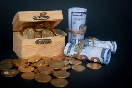 Gold coins in treasure chest and bank notes isolated on dark background cover. Copy space and wealth conceptの写真素材