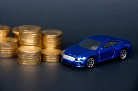 Kuala Lumpur, Malaysia - July 2022 : Miniature toy car of Bentley Continental GT with gold coins on black cover background. Copy space.のeditorial素材