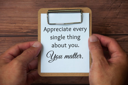 Hand holding paper holder board with text on white notepad - Appreciate every single thing about...