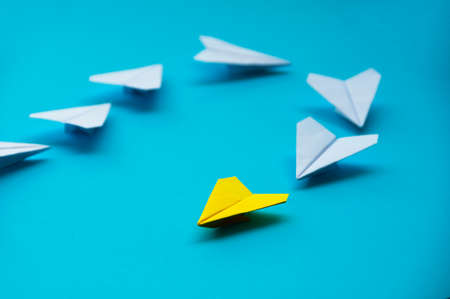 Yellow paper plane origami leading white planes on blue background. Leadership skills concept.の写真素材
