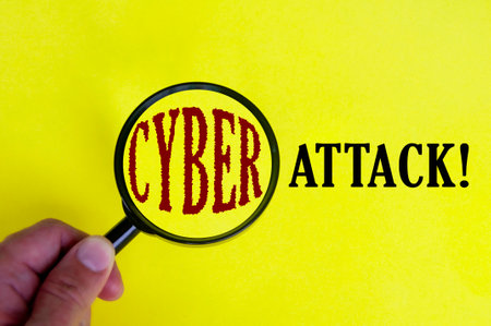 Cyber attack text on yellow cover with hand holding magnifying glass. Internet security concept.の写真素材