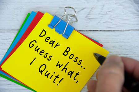 Dear boss, guess what, I quit text on yellow notepad on wooden desk background. Employment and...