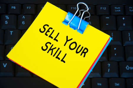 Sell your skill text on yellow notepad on black keyboard background