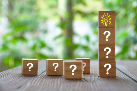 Wooden cube block with light bulb surrounded by questions marks. Solution and idea concept.の写真素材