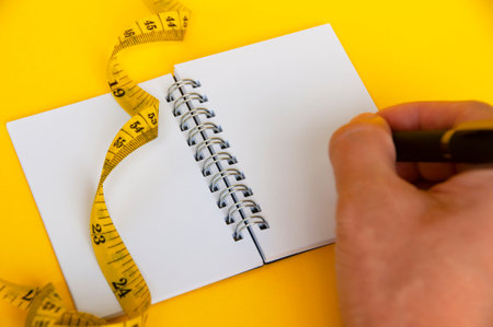 Blank notepad and measuring tape with customizable space for text or ideas. Copy space and weight loss conceptの写真素材