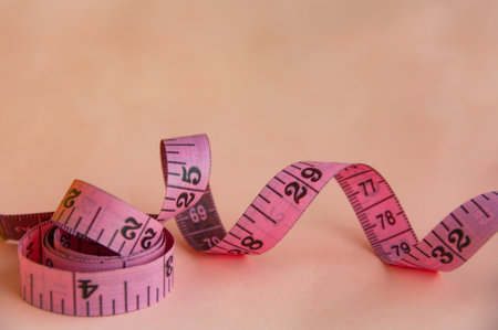 Red measuring tapes on pink cover background with customizable space for text or ideas. Copy space...