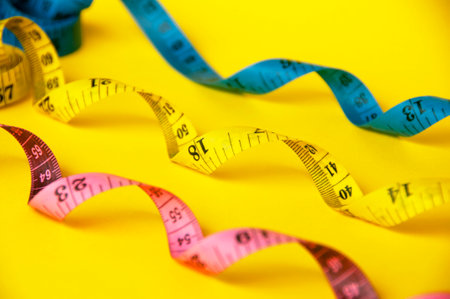Red, yellow and blue measuring tapes on yellow cover background. Copy space and weight loss concept.の写真素材