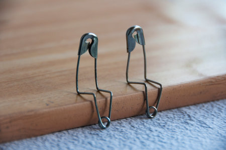 Two safety pins sitting on brown wood having a conversation. Friendship and lovers concept.