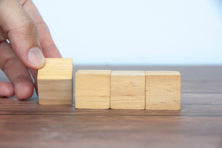 Hand turning blank wooden cubes customizable space for text or ideas. Copy space.の写真素材