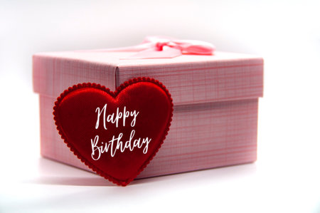 Happy birthday text on heart shape with pink color present on white background.の写真素材