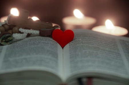 Red heart shape on Holy Bible with candle lights and vintage color background. Customizable space for text or ideas. Copy space.の写真素材