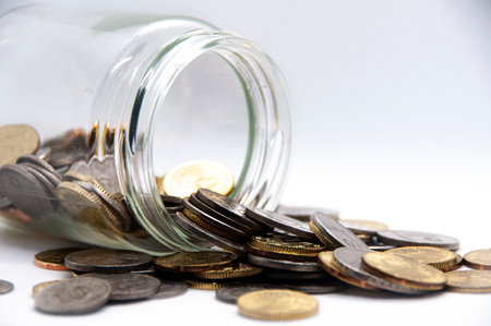 Close up of coins in a jar on white background with customizable space for text or ideas. Business...