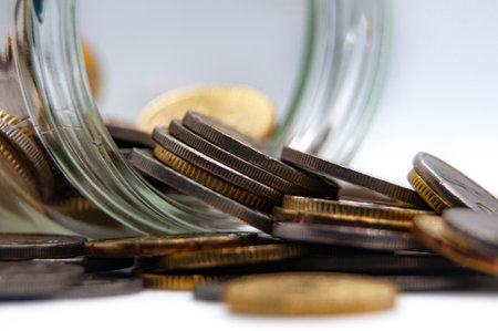Close up of coins in a jar on white background with customizable space for text or ideas. Business and investment concept.の写真素材