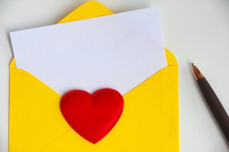 Love letter with white paper sheet in yellow paper envelope with customizable space for text. Love concept and copy space.の写真素材