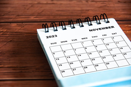 November 2023 white desk calendar on wooden table background. Calendar concept and copy spaceの写真素材