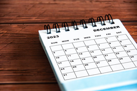 December 2023 white desk calendar on wooden table background. Calendar concept and copy space
