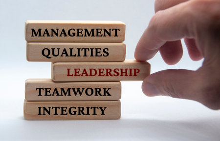 Management, qualities, leadership, teamwork and integrity text on wooden blocks with white...