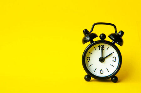 Alarm clock pointing at 2 am or pm with customizable space for text or ideas. Copy space with yellow background.の写真素材