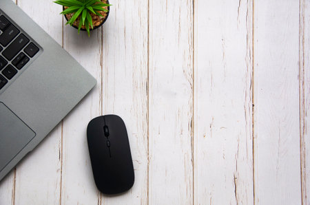 Top view of laptop, table plant and mouse on white wooden table with customizable space for text. Copy space.の写真素材
