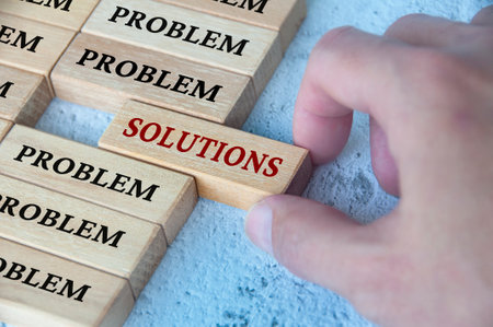 Hand placing wooden blocks with solutions text text on wooden blocks. Solutions to problems concept.の写真素材