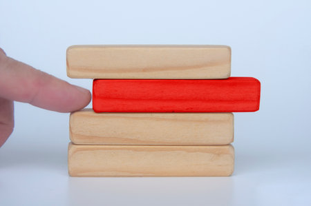 Hand pushing red wooden block from other stacked wooden block. Customizable space for text. Copy...