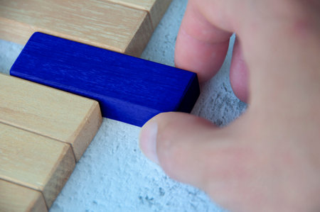Hand pulling blue wooden block from other wooden block with customizable space for text. Copy space.