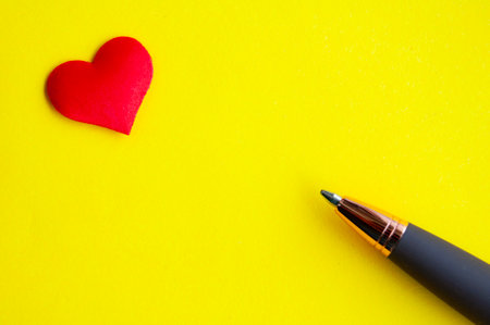 Heart shape and pen on yellow background cover with customizable space for text or message. Love concept and copy spaceの写真素材