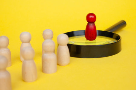 Leadership concept, red figure on magnifying glass leading the rest of figures on yellow cover background.の写真素材