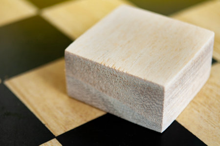 Side view closeup of wooden cube on empty chess board