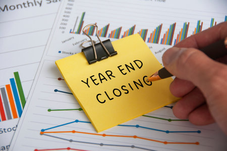 Hand writing Year End Closing text on sticky note with statistic and graph backgroundの写真素材
