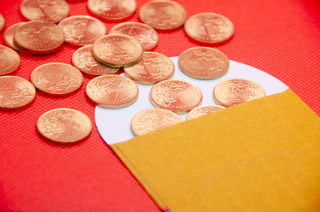 Close up of yellow envelope and golden coins on red cover background.の写真素材