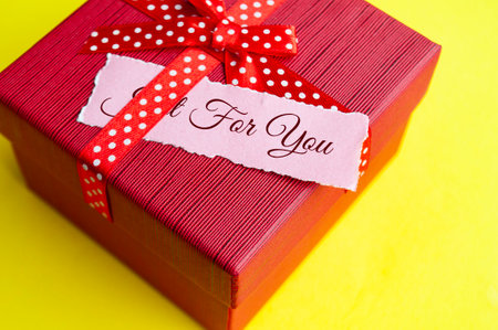 Just for you text on torn paper on top of present on red background.