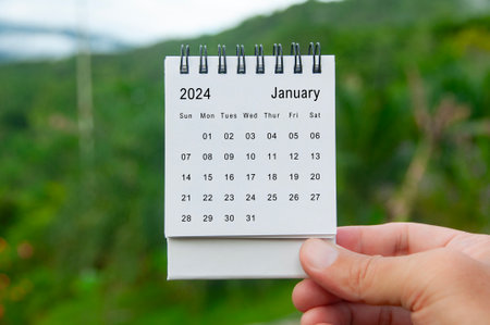 Hand holding January 2024 white calendar with nature background. Holiday and calendar concept.の写真素材