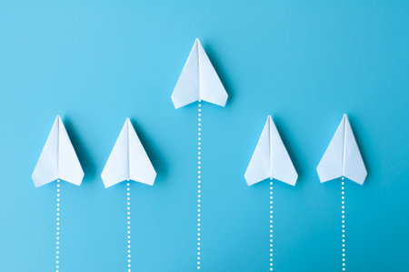 Top view of white paper airplanes origami flying on blue background.の写真素材