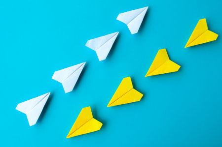 Top view of a white and yellow paper airplanes origami flying at different direction.