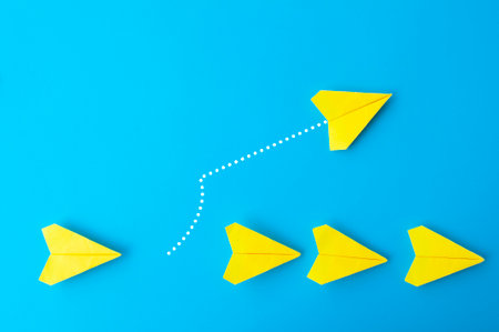 Top view of yellow paper airplanes with one flying at different direction.