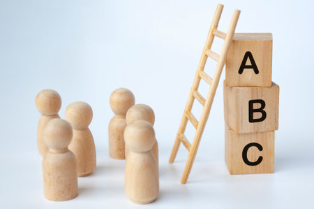 ABC text on wooden cubes with ladder and doll figures on white background. Knowledge concept.の写真素材