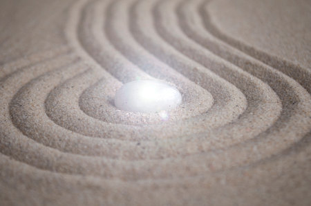 Shining Zen stone in the middle of curve lines on sand.の写真素材