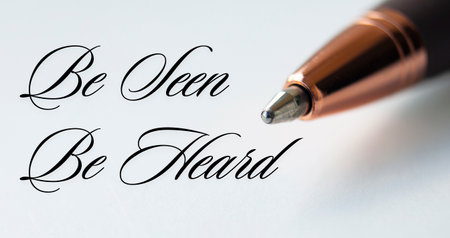 Be seen be heard text with closeup pen on white cover background.