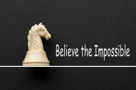 Believe the impossible text with black knight chess on white cover background.の写真素材