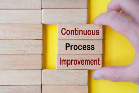 Hand pulling wooden blocks with continuous process improvement text. Business culture and...