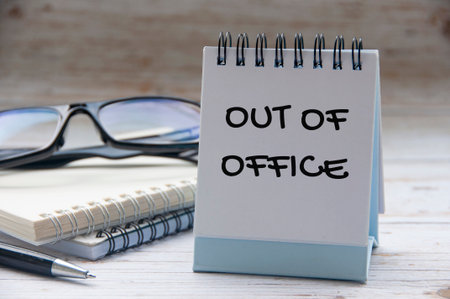 Out of office text on white notepad with notes and glasses background.の写真素材