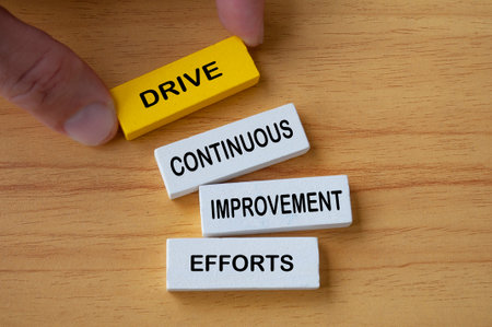 Top view of hand holding wooden blocks with text Drive Continuous Improvement Efforts. Process...