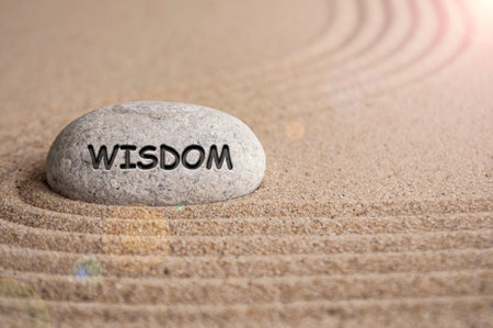Wisdom text engraved on stone with sand beach background. Peace of mind concept.の写真素材