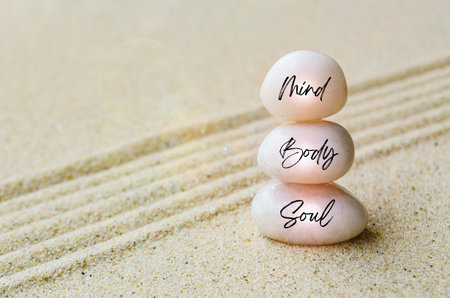 Mind, Body and Spirit text engraved on white zen stones with sand background. Peace and harmony conceptの写真素材
