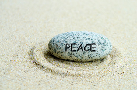 Peace text engraved on stone with sand beach background.の写真素材