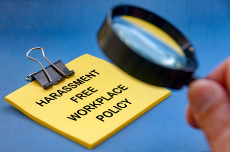 Harassment free workplace policy written of yellow pad with blurred magnifying glass. Safe workplace concept.の写真素材